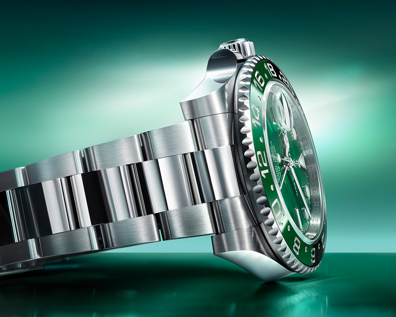 Close-up image of a stainless steel wristwatch band and partially visible watch case with a metallic sheen, reflecting light.